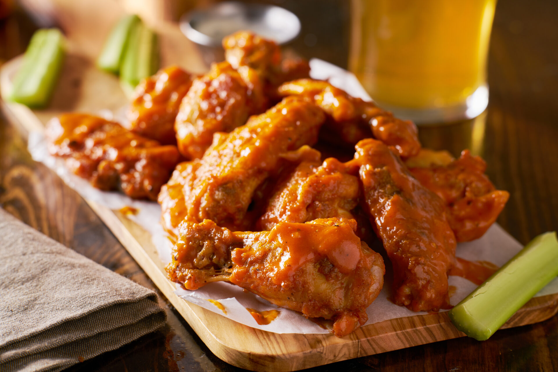 sauced buffalo chicken wings on wooden board with celery